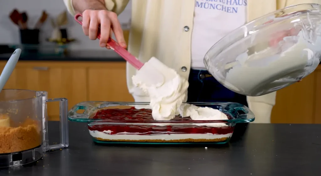 Final creamy layer spread over cherry filling in Cherry Yum Yum dessert