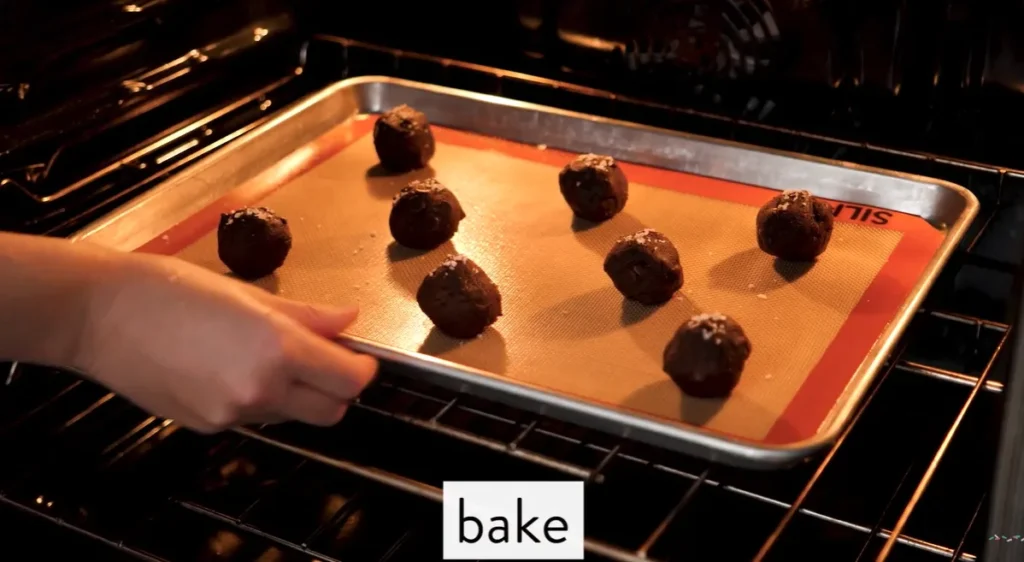 Salted caramel chocolate fudge cookie dough balls baking on a lined sheet pan