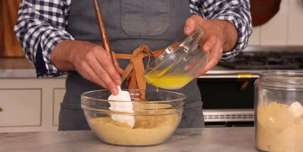 Melted butter being mixed into graham cracker crumbs for Banoffee Pie crust