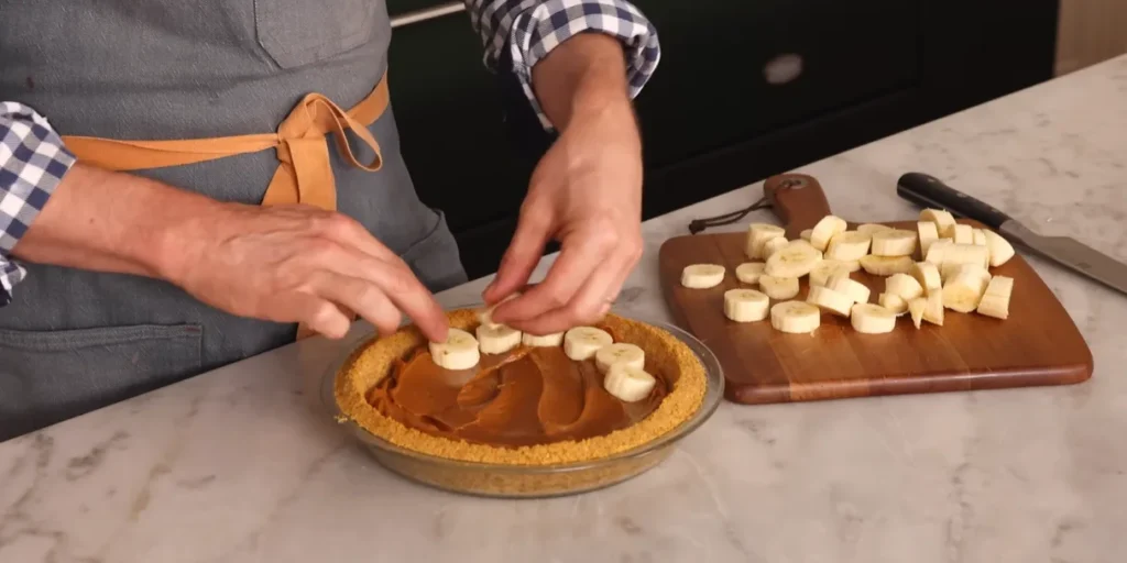 Banana slices arranged over the dulce de leche layer in Banoffee Pie