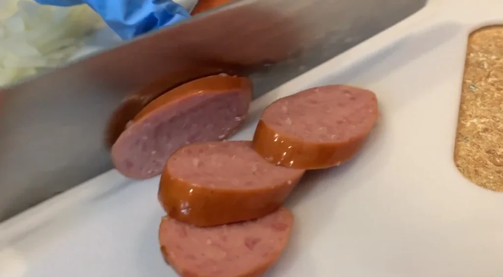 Smoked sausage sliced into rounds on a cutting board for Cajun sausage pasta