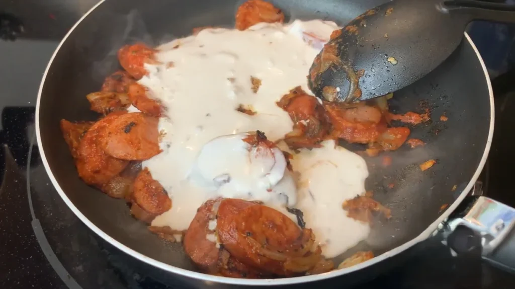 Smoked sausage and vegetables simmering in creamy Cajun sauce in a skillet
