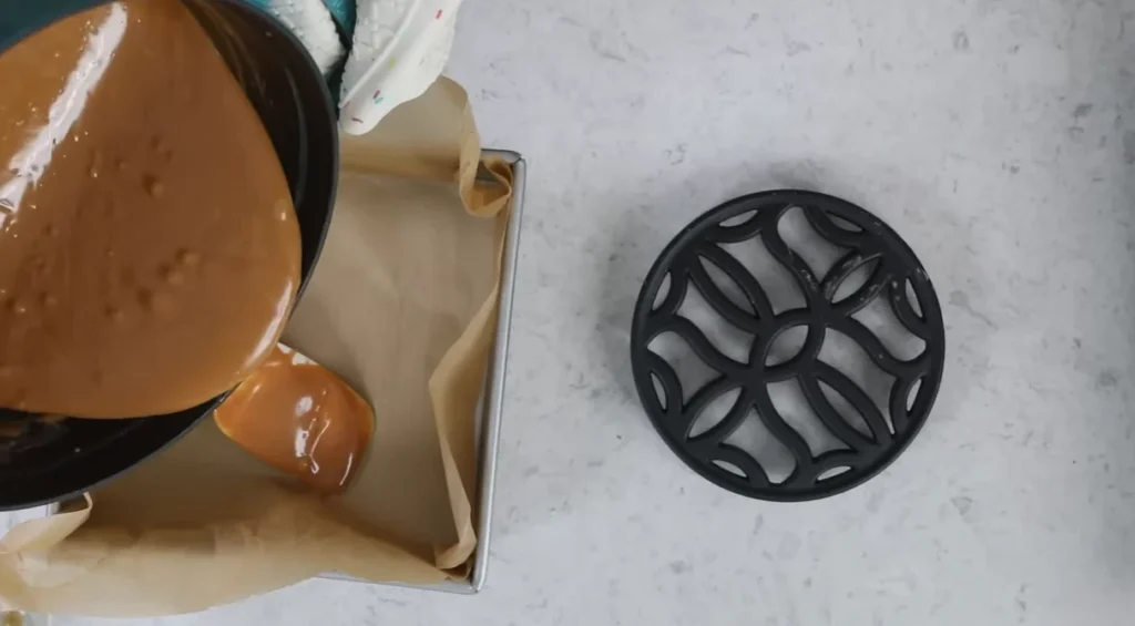 Hot homemade caramel poured into a parchment-lined square pan to cool