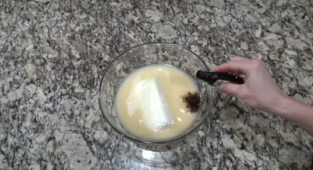Vanilla extract added to cream cheese and condensed milk mixture for cherry cream cheese pie