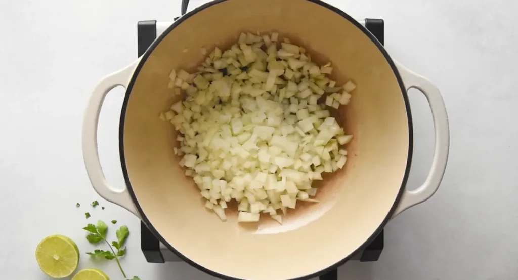 Diced yellow onions cooking in a large pot for chicken enchilada soup