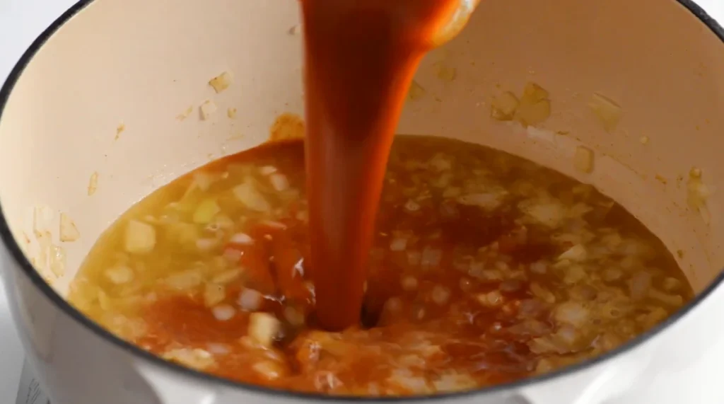 Red enchilada sauce poured into the chicken enchilada soup base
