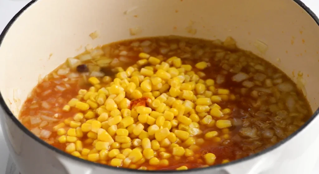 Corn added to the simmering chicken enchilada soup with black beans and vegetables