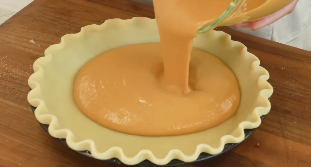 Creamy pumpkin pie filling poured into an unbaked pie crust
