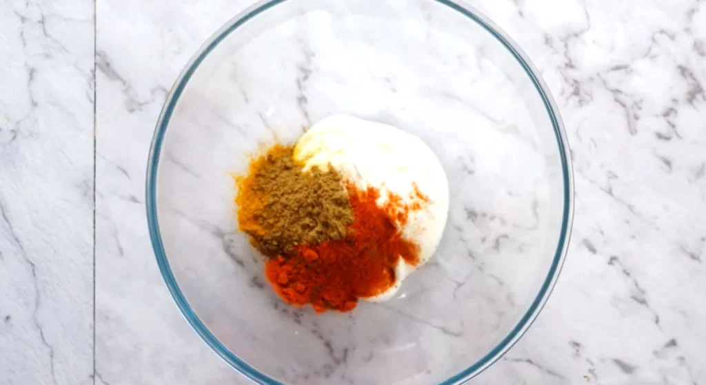 Butter chicken marinade ingredients mixed with yogurt, spices, ginger, and garlic in a bowl