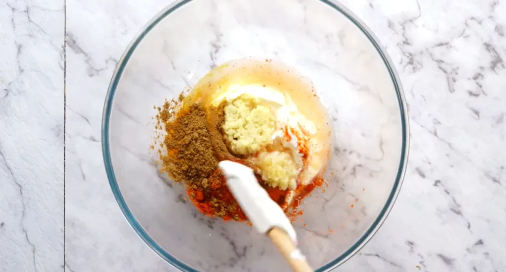 Yogurt butter chicken marinade with ginger, garlic, and Indian spices being mixed in a bowl