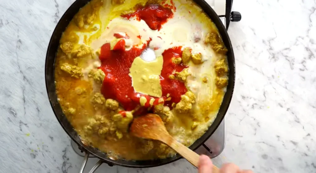 Butter chicken simmering with tomatoes, cream, and spices in a skillet
