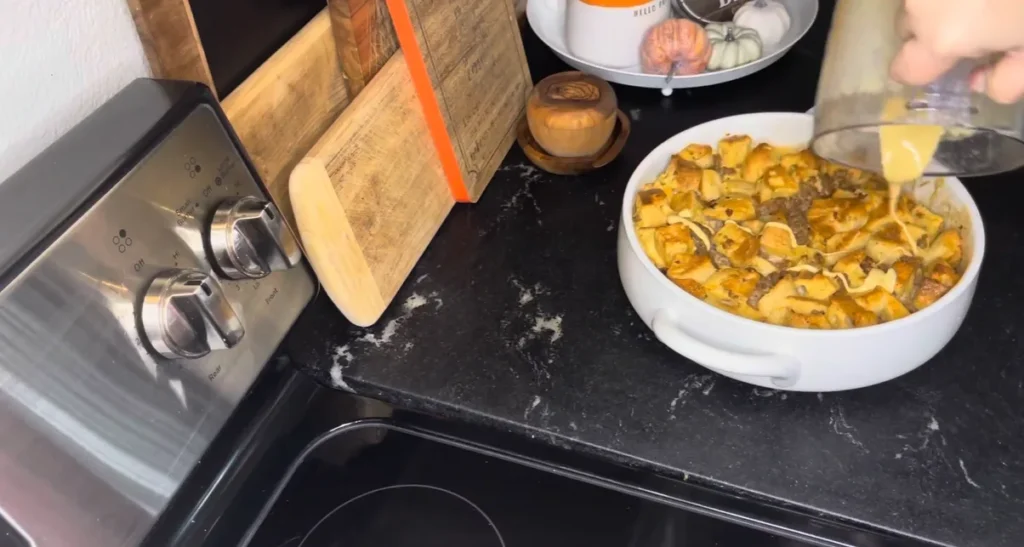 Drizzling homemade Hollandaise sauce over Eggs Benedict Casserole