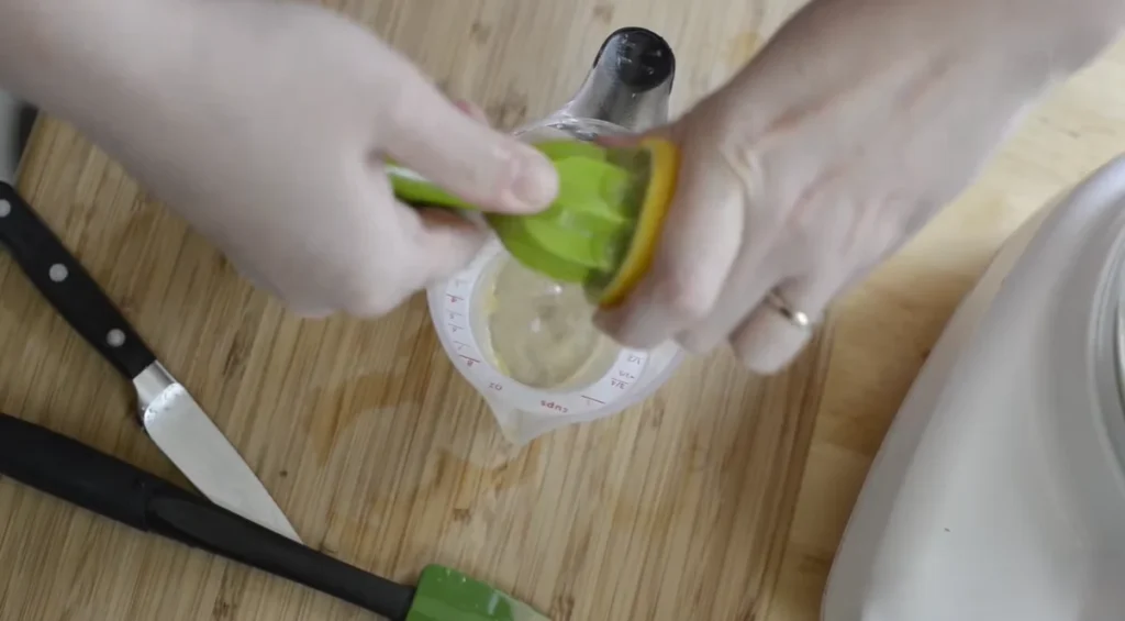 Fresh lemon juice being squeezed for homemade hummus before adding it to the food processor.
