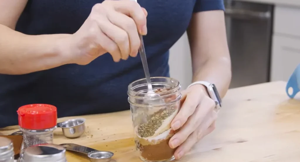 Homemade taco seasoning spices being added to a jar