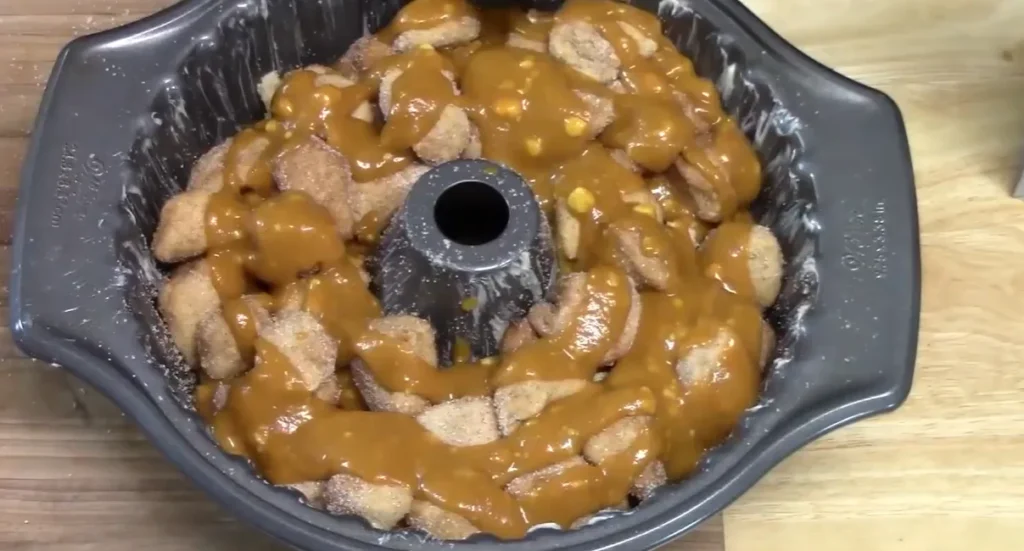 Pumpkin caramel sauce poured over spiced biscuit pieces in a Bundt pan