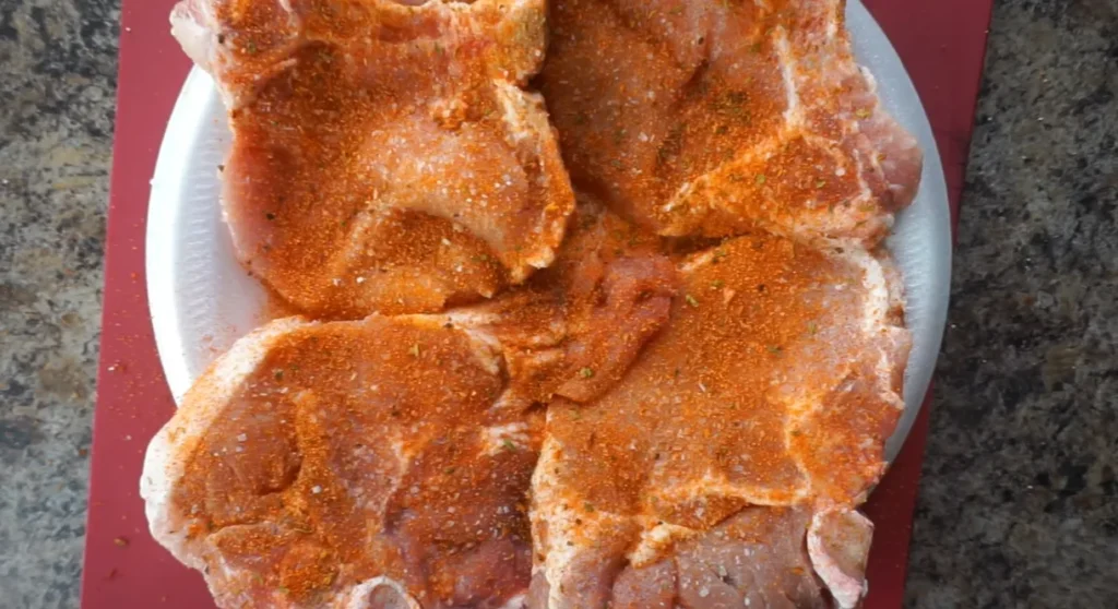 Bone-in pork chops seasoned with smoked paprika, garlic powder, onion powder, salt, and black pepper before cooking.