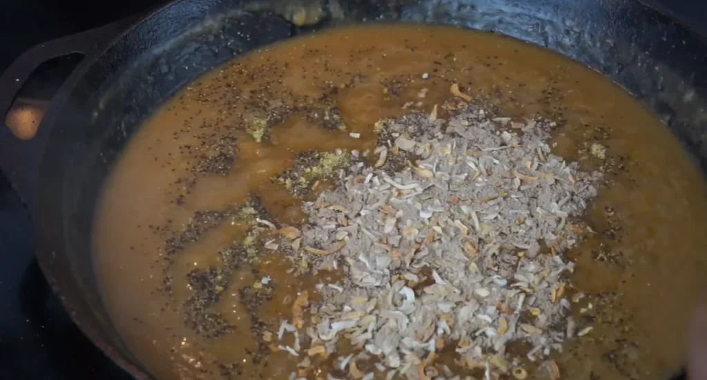 Chicken broth, seasonings, and aromatics simmering together to make rich Southern onion gravy.