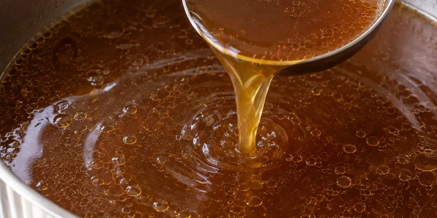 Ladle lifting beef broth from a stainless steel pot
