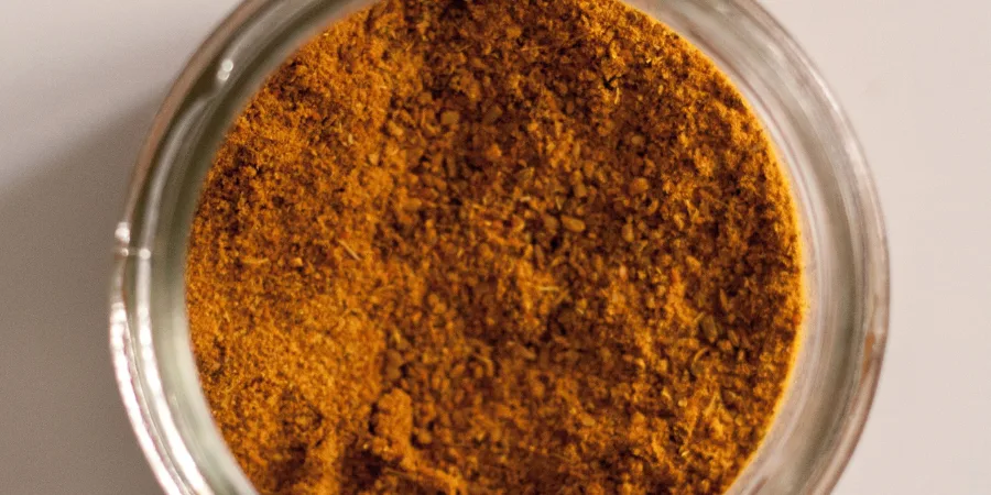 Glass jar of orange-yellow curry powder seen from above