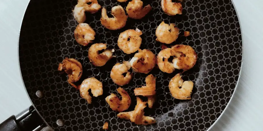 Golden seared shrimp cooking in a black non-stick pan