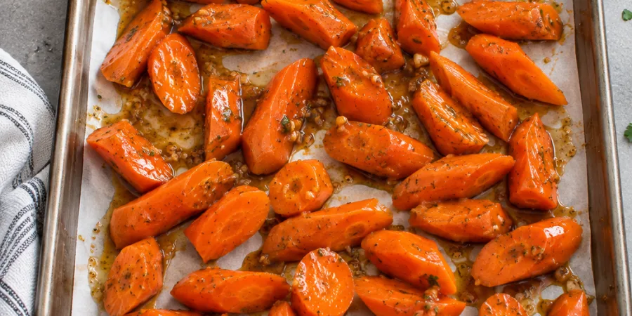 Glazed carrots in a single layer on a parchment lined baking sheet