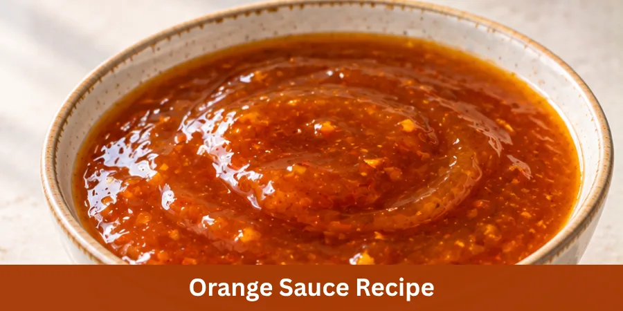 A smooth glossy orange sauce in a simple ceramic bowl on a clean kitchen counter with a spoon nearby, showing a finished homemade sauce.