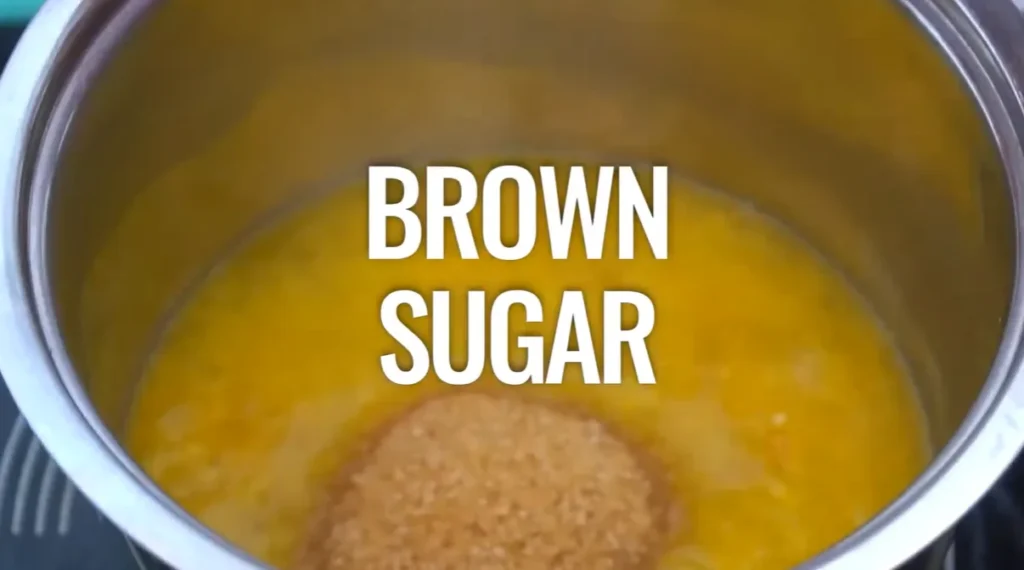 Adding light brown sugar to orange juice in a saucepan for orange sauce