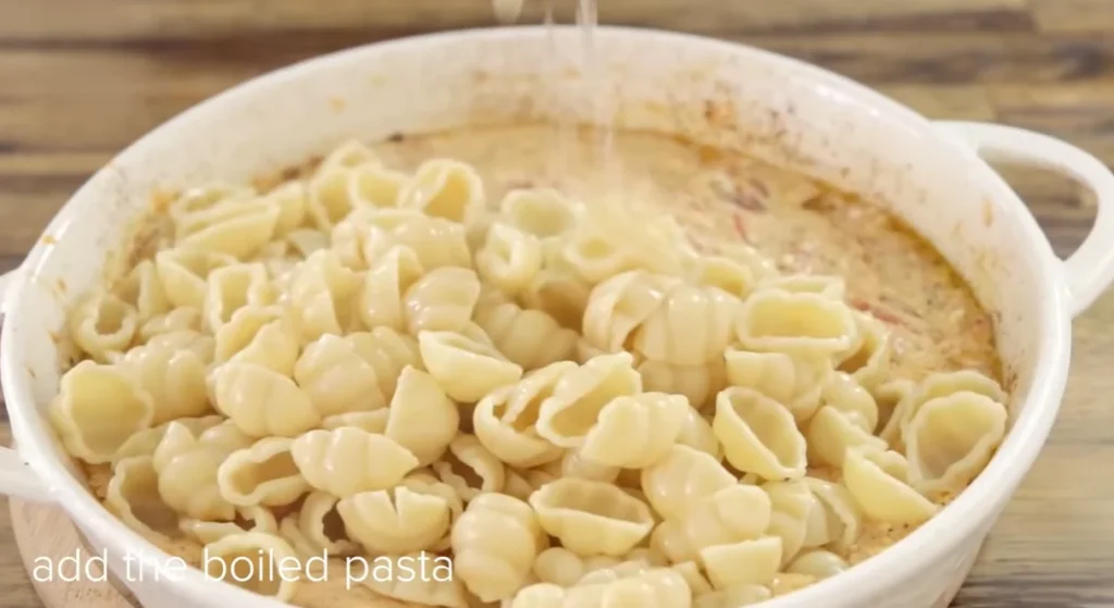 Boiled shell pasta added to the creamy feta and tomato sauce in a baking dish