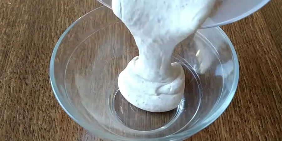 Smooth thick creamy sauce being poured into a glass bowl to check its consistency