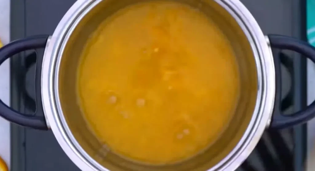 Fresh orange juice heating in a stainless steel saucepan on the stove
