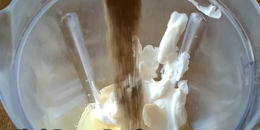 Ground black pepper falling onto the creamy sauce ingredients
