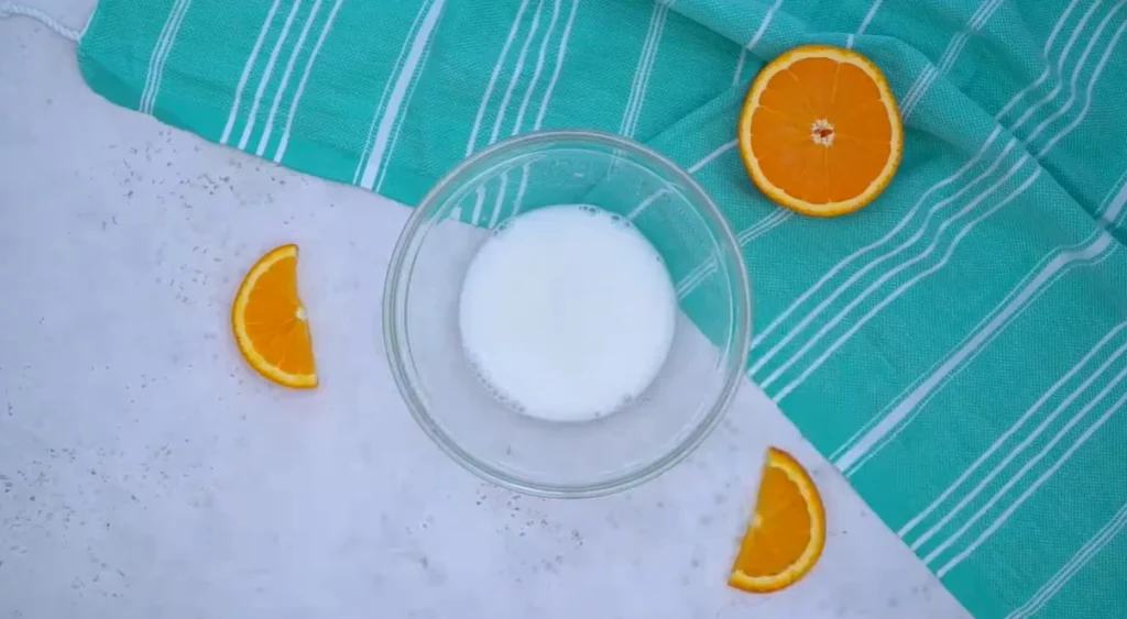 Smooth white cornstarch slurry in a glass bowl, ready to thicken orange sauce