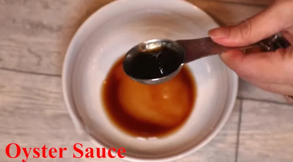 Spoonful of glossy dark oyster sauce held over a white bowl