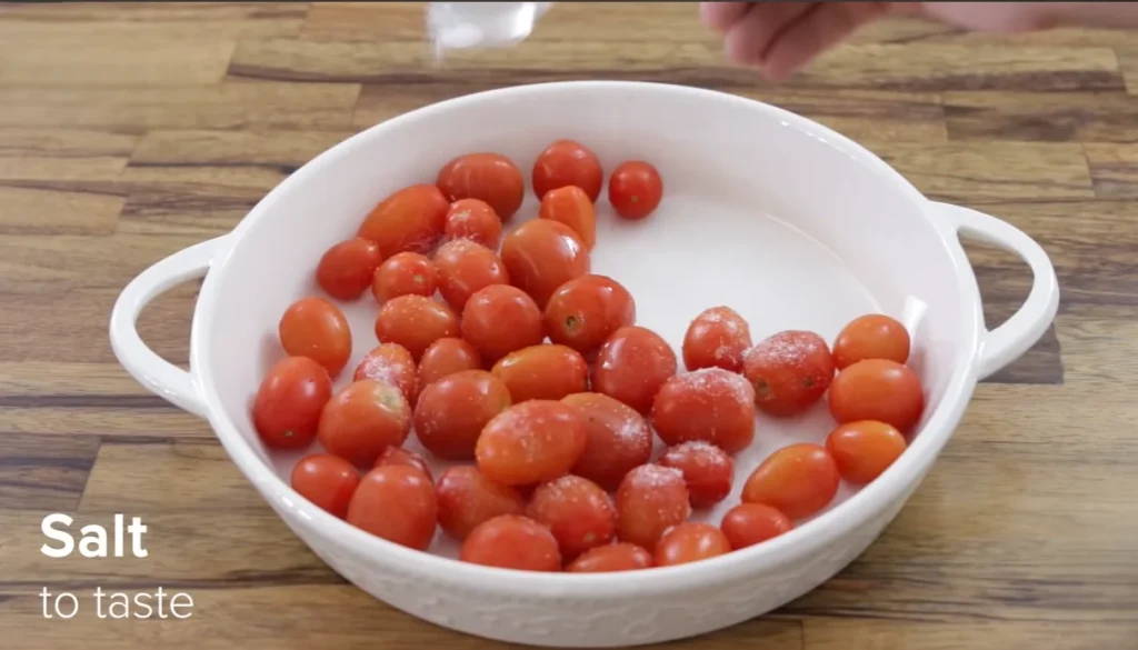Sprinkling salt over cherry tomatoes in a baking dish