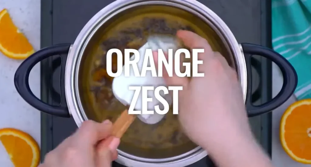 Stirring fresh orange zest into the orange sauce in a saucepan