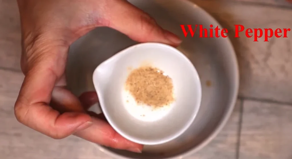 White pepper powder in a small white dish held in one hand