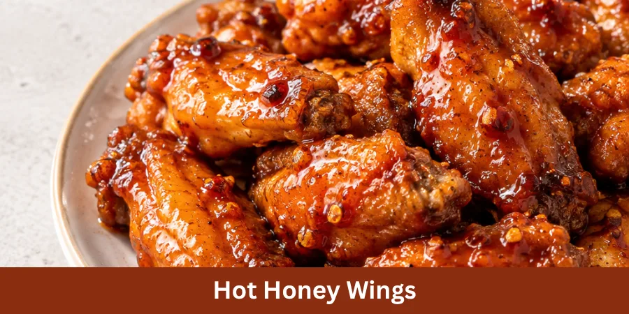 A plated serving of Hot Honey Wings with a glossy sweet-spicy coating, arranged neatly on a simple plate with a clean neutral kitchen setting in the background. The image presents the finished wings as a complete homemade recipe.